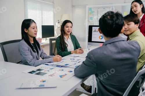 Preview: Asian business team discussing financial charts in office meeting