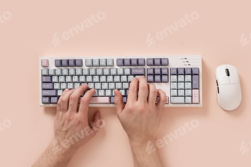 Preview: Mans hands typing on keyboard on pink background. View from above. Flat lay.