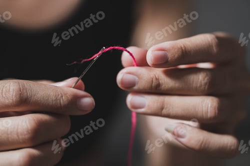 Preview: Woman fingers threading a needle