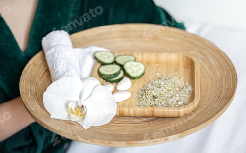 Vista previa: Spa composition with wooden plate with cucumber slices and sea salt.