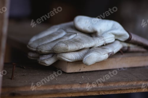 Preview: Closeup of a pair of dirty white leather gloves on a wooden board