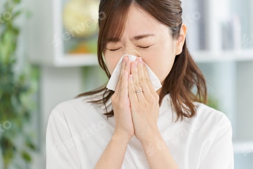 Preview: A woman blowing her nose due to rhinitis