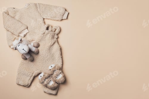 Preview: Beige baby teddy bodysuit, sweatshirt, soft toy sheep on pastel backgroundd. Styled newborn clothes