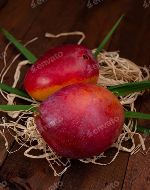 Preview: mango fruits with leaves on straw and wooden table