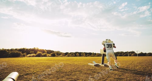 Preview: Lone football player doing tackling drills on a sports field