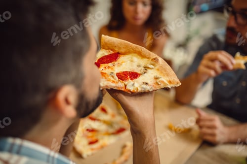 Preview: Cropped photo of group of young people eating pizza at home