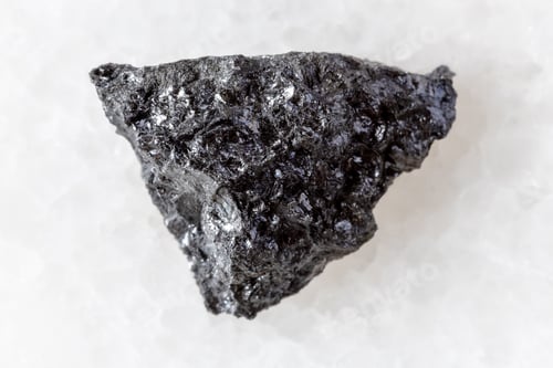 Preview: sample of rough hulsite mineral on white marble