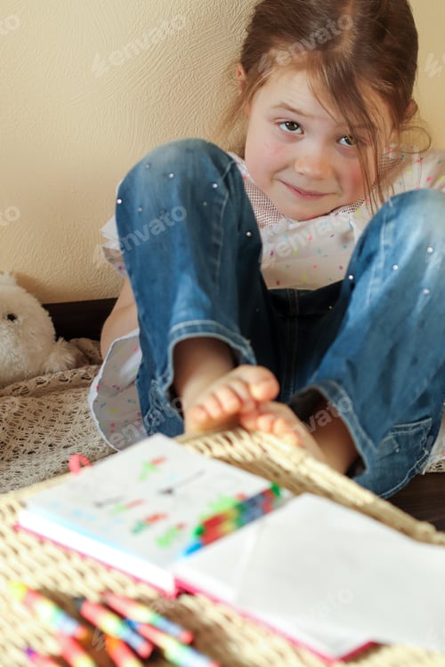 Preview: A little girl 6 years old is resting and thinking about a plot for drawing