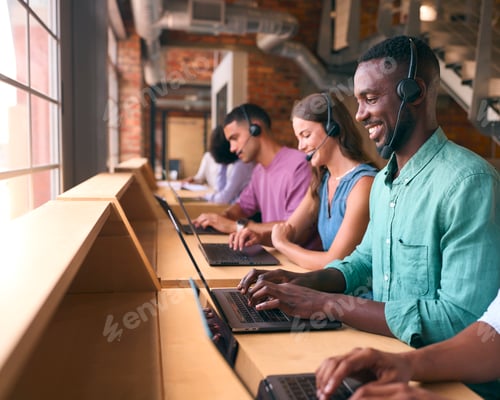 Preview: Multi-Cultural Customer Support Or Telesales Team In Modern Open Plan Office Wearing Headsets