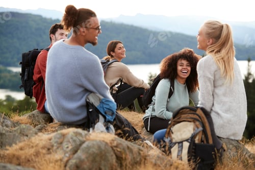 Preview: Five young adult friends sit talking at the summit after a mountain hike, close up
