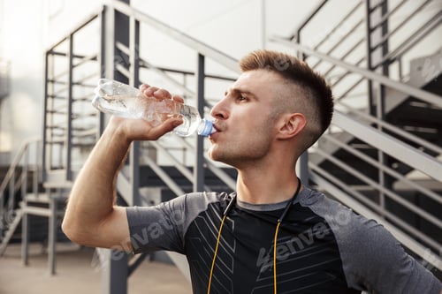Preview: Image of unshaven caucasian sportsman drinking water while working out