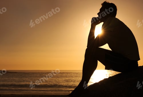 Preview: Searching for lifes answers. Silhouette of a thoughtful man sitting by the ocean - copyspace.