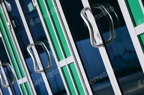 Preview: Chrome door handle and glass of modern aluminium door outside the office building