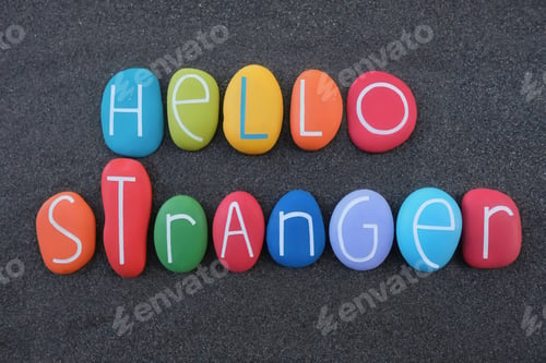 Preview: Hello stranger, english phrase composed with colored stone letters over black volcanic sand