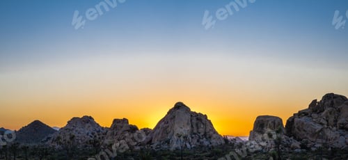 Preview: Stunning desert landscape with vibrant red-orange sunset sky illuminating the natural rocky terrain