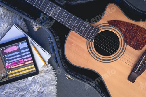 Preview: Acoustic guitar and digital tablet with a music application, top view.