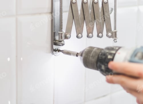Preview: The hands of a young caucasian guy are tightening a screw on a metal fastener using a drill