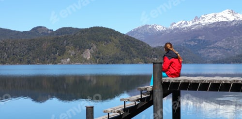 Preview: Girl in Red Jacket Sitting on Wooden Pier at Lake Hermoso Patagonia Argentina