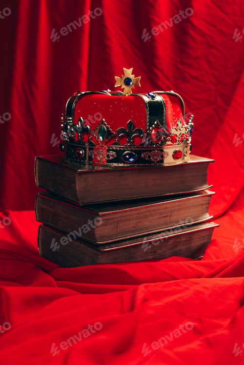 Preview: ancient golden crown with gemstones on books on red cloth