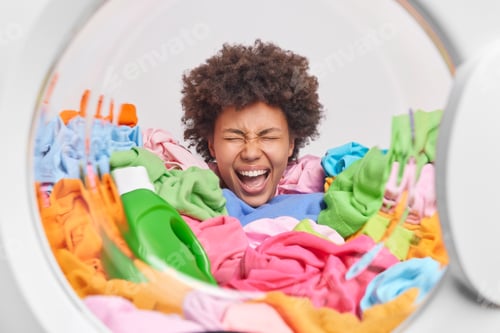 Preview: Housework and daily activities concept. Emotional woman with curly hair sticks head in heap of multi