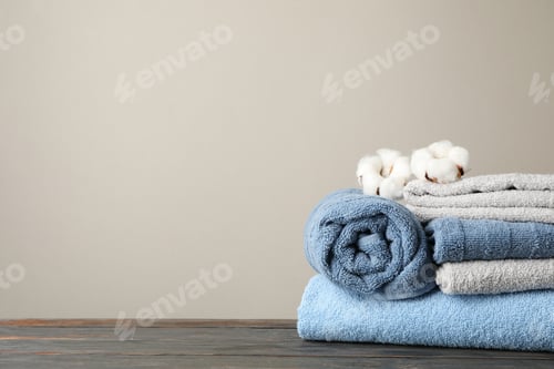 Preview: Folded towels and cotton on wooden table against grey background, space for text