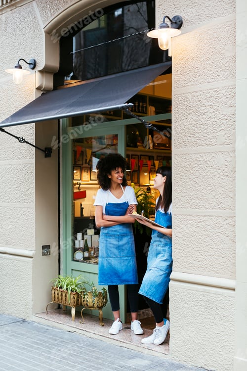 Preview: Two happy women standing in entrance door of a store