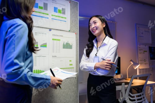 Preview: Two asian businesswomen discussing company strategy during a night meeting in the office