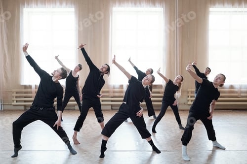 Preview: Group of young active dancers in black t-shirts and pants stretching one arm
