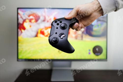 Preview: In front of the monitor in my hand is a video game controller. Video game gamepad in hand