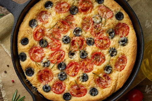 Preview: Focaccia, pizza in skillet, italian flat bread with tomatoes, olives and rosemary. Wooden table