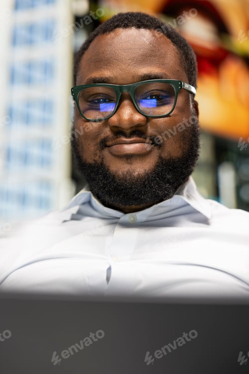 Preview: Portrait of black man sitting on bench with laptop navigating online websites