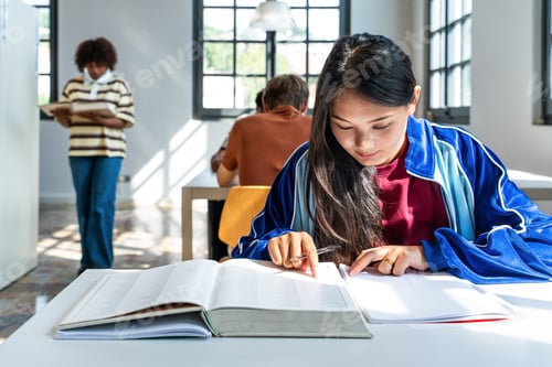 Preview: Young chinese woman studying at table in university library