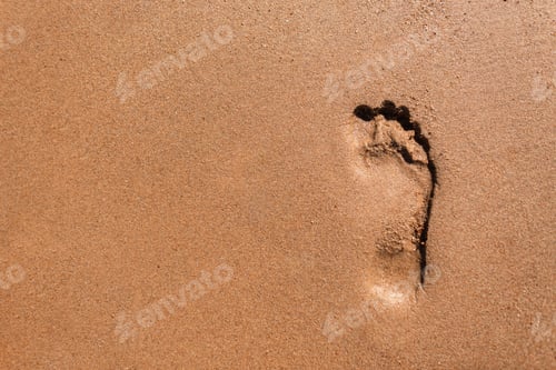 Preview: Human footprint in the sand on the beach with a wave near the sea, top view. Summer