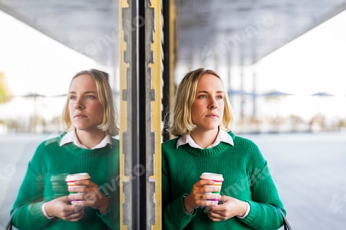 Preview: Businesswoman holding coffee cup while looking away outdoors