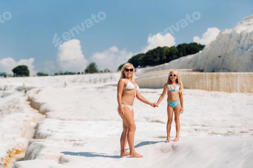 Aperçu: a little girl with her mother in bathing suits and sunglasses on a White mountain, a Family on a