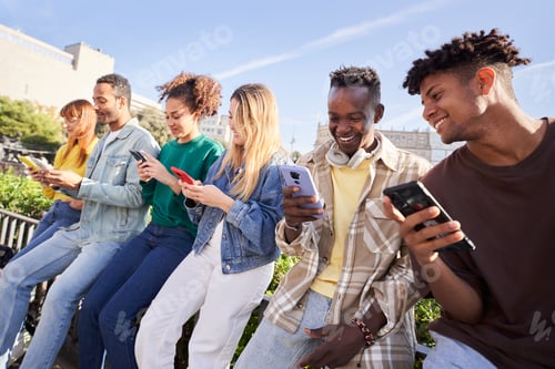 Preview: Group of young mixed race people with mobile phones. Excited students using technological devices