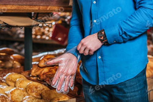 Preview: cropped shot of man wearing disposable glove in grocery shop