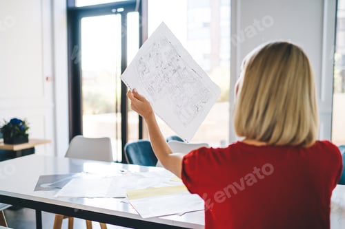 Preview: Businesswoman looking at draft in light while speaking on smartphone