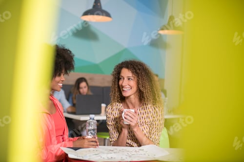 Preview: Two women talking in office lounge