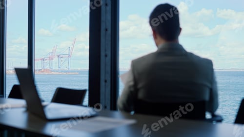 Preview: Office manager checking documents at panorama window rear view. Person reading