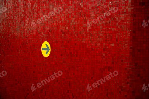 Preview: Yellow right arrow on a red wall on a Subway station