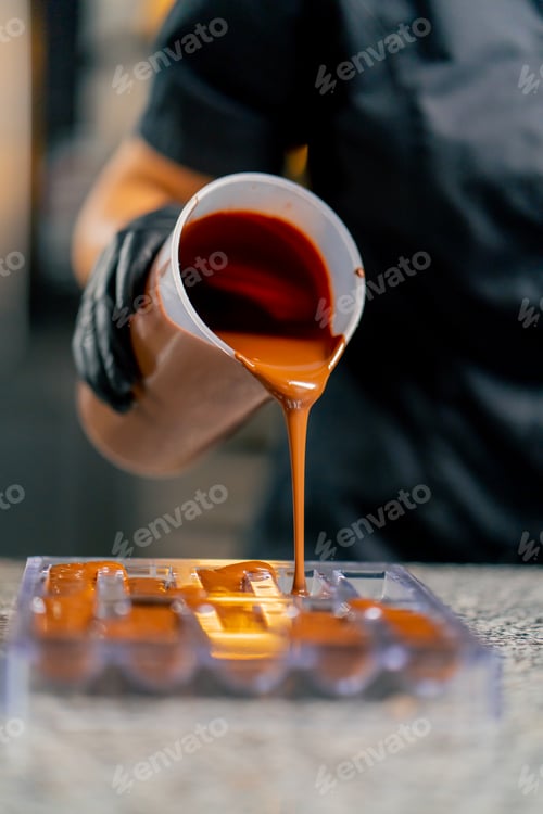 Preview: Melted hot chocolate is poured into a transparent chocolate mold for making natural candies