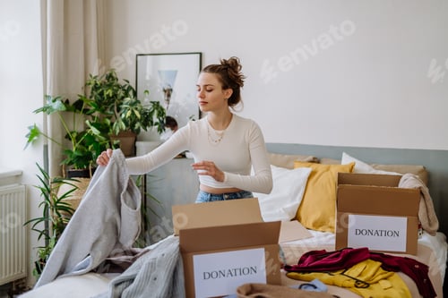 Preview: Young woman giving her clothes to charity.