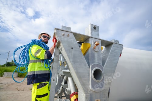 Preview: Windturbine inspector wearing Personal protective equipment working at wind turbines farm .