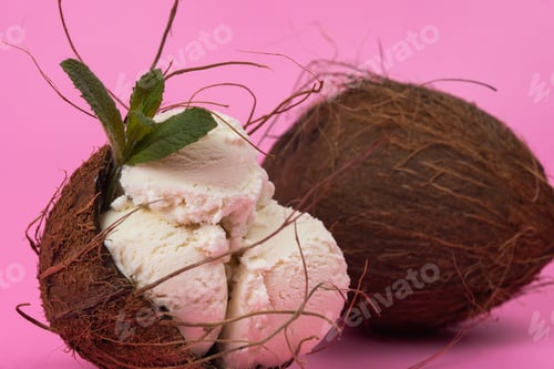 Preview: Vanilla ice cream balls in an empty coconut decorated with mint leaves on a pink background