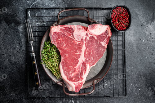 Preview: Fresh raw T-bone marbled beef meat Steak on a steel tray. Black background. Top view