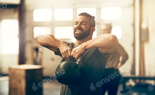 Preview: Smiling young man lifting a dumbbell while working out