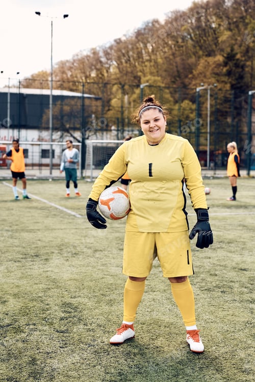 Preview: Portrait of female goalkeeper on soccer field looking at camera.