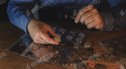 Preview: A man holds an old coin in his hands and examines it under a magnifying glass, money, numismatics.