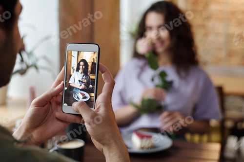 Preview: Guy with smartphone taking photo of his girlfriend with rose and cheesecake